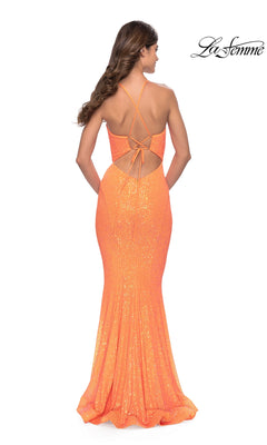 Woman in the Bright Long Sequin La Femme Prom Dress 31199, shown from behind, featuring an orange mermaid silhouette with an open back and crisscrossed straps. "La Femme" logo appears in the top right corner.