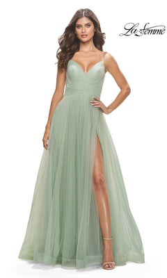 A woman wears the La Femme A-Line Long Tulle Prom Dress 31204 in light green, featuring a floor-length silhouette, thigh-high slit, spaghetti straps, and tulle overlay, standing against a plain white background.