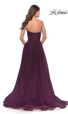 A woman faces away in the Strapless Long Prom Ball Gown: La Femme 31205, a floor-length dark purple A-line dress with tulle skirt, slight train, and flattering fitted bodice. The La Femme logo appears in the corner.