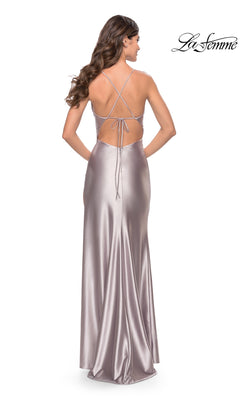A woman faces away in the La Femme Metallic Jersey Prom Dress 31208, a floor-length gown with a low open back and crisscross spaghetti straps.