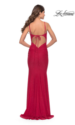 A woman models the La Femme Backless Shimmer Designer Prom Dress 31218— a fitted, floor-length red gown with spaghetti straps, tie-back detail, and subtle sparkle. The "La Femme" brand appears in the top right corner.