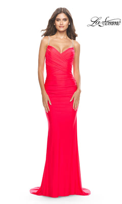 Woman wearing a hot coral La Femme Ruched Fitted Designer Prom Dress 31222 with v-neck, thin straps, and mermaid silhouette, posing against a white background with the "La Femme" logo in the corner.