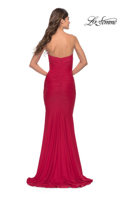 A woman stands with her back to the camera wearing the La Femme Classic Strapless Tight Prom Dress 31226, a floor-length red gown with ruched detailing.