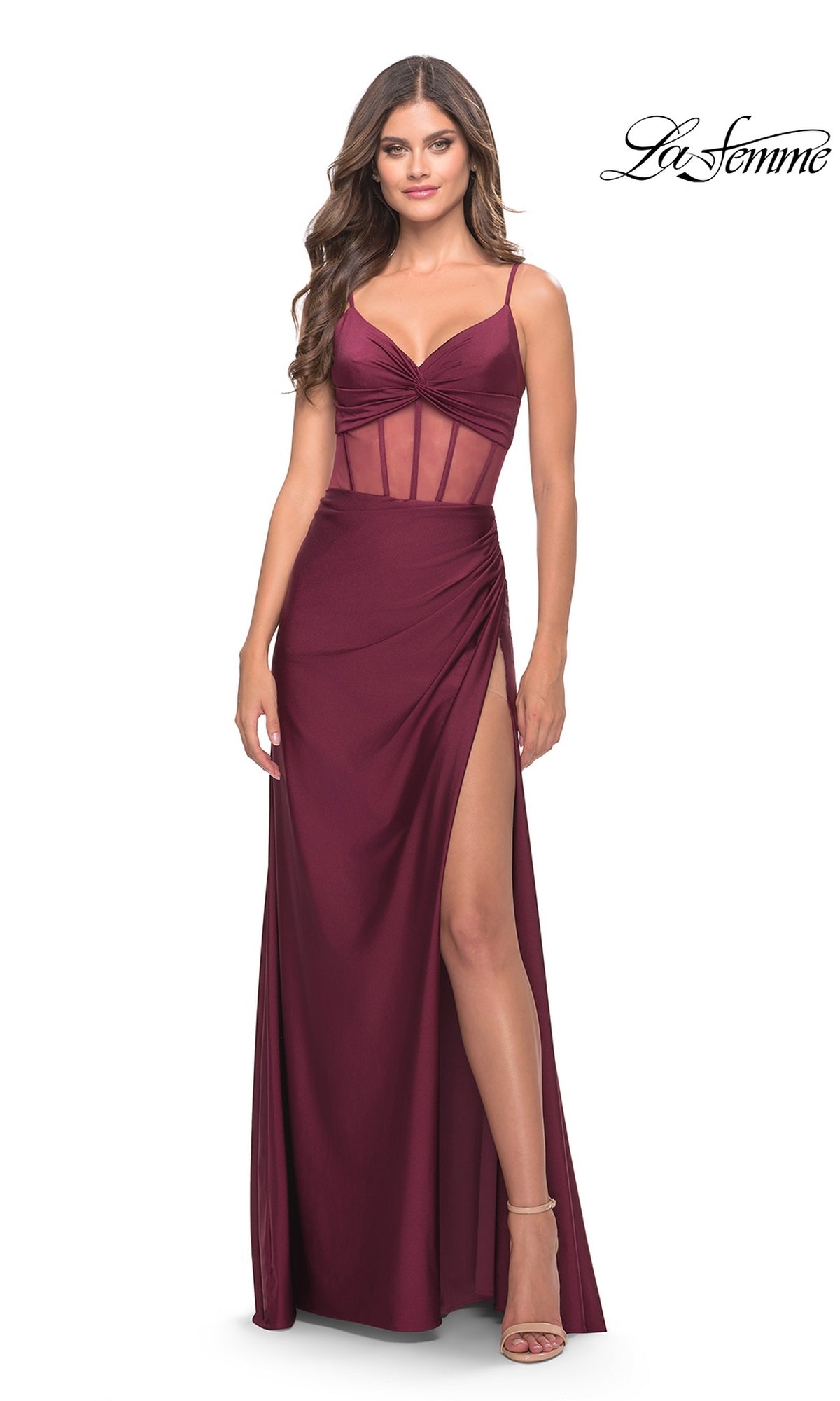 A woman wears the La Femme V-Neck Sheer-Corset Long Prom Dress 31229—sleeveless, burgundy, with sheer corset bodice paneling, a left high slit, and thin straps. The La Femme logo appears in the top right corner.