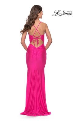 A woman stands facing away, wearing the La Femme Backless Tight Shimmer Prom Dress 31237 in bright pink with a floor-length design, open back, and crisscross straps. The "La Femme" logo appears in the upper right corner.
