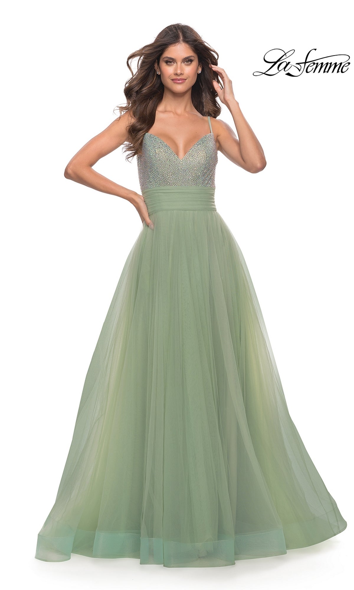 A woman in a light green Beaded-Bodice Tulle Prom Ball Gown 31238 with a v-neck, fitted beaded bodice, and thin straps stands with one hand on her hip. The La Femme logo appears in the top right corner.