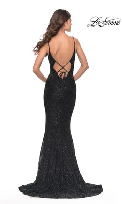 A woman models the La Femme Beaded Long Black Lace Prom Dress 31257 with sequins, a low open back, and crisscross straps against a white background. The La Femme logo is visible in the corner.