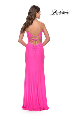 A woman models the La Femme Side-Slit Backless Long Prom Dress 31329 in bright pink, featuring thin straps, lace-up back detailing, and a floor-length design. The "La Femme" logo appears in the top right corner.
