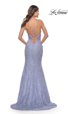 A woman wearing the La Femme Long Lace Mermaid Prom Dress 31354 in lavender stands facing away, highlighting its open back with crisscross lace-up detail and the elegant mermaid lace design.