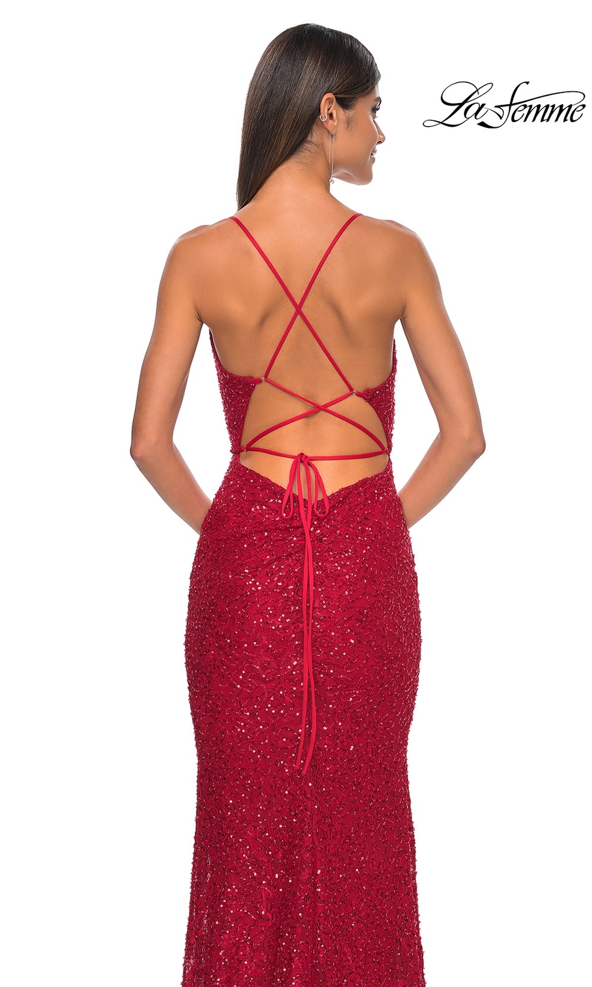 A woman faces away, wearing the La Femme Long Beaded Lace Prom Dress 31359—a red, sparkly formal gown with crisscross spaghetti straps and tie closure. The La Femme logo is visible in the top right corner.