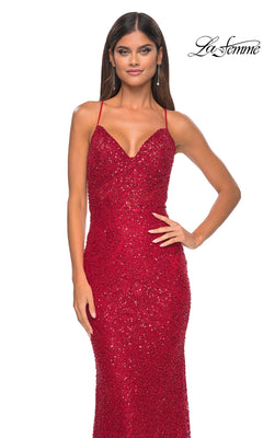 Woman in a fitted, sparkling red La Femme Long Beaded Lace Prom Dress 31359 with thin straps, posing hand on hip against a plain white background. "La Femme" logo appears in the top right corner.