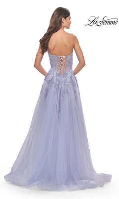 A woman in the La Femme Strapless Sweetheart Long Prom Dress 31363, with floral appliqués, faces away to show off its elegant lace back details.