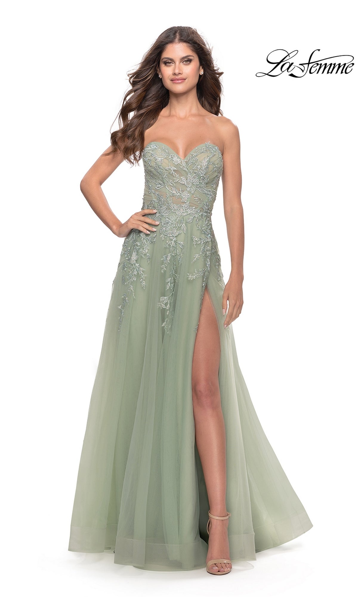 A woman showcases the La Femme Strapless Sweetheart Long Prom Dress 31363 in light green, featuring lace floral embroidery, a thigh-high slit, and a flattering silhouette, standing confidently with one hand on her hip against a white background.