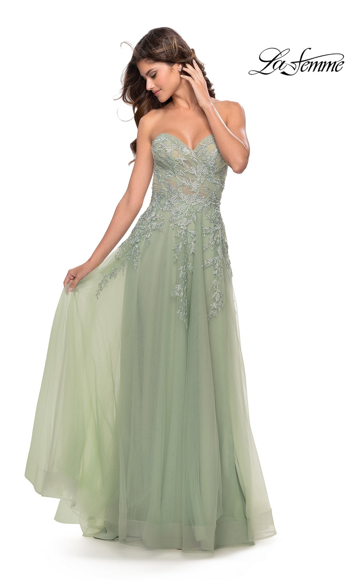 A woman poses against a white background in the La Femme Strapless Sweetheart Long Prom Dress 31363, a light green gown with lace floral embroidery and a flowing tulle skirt.