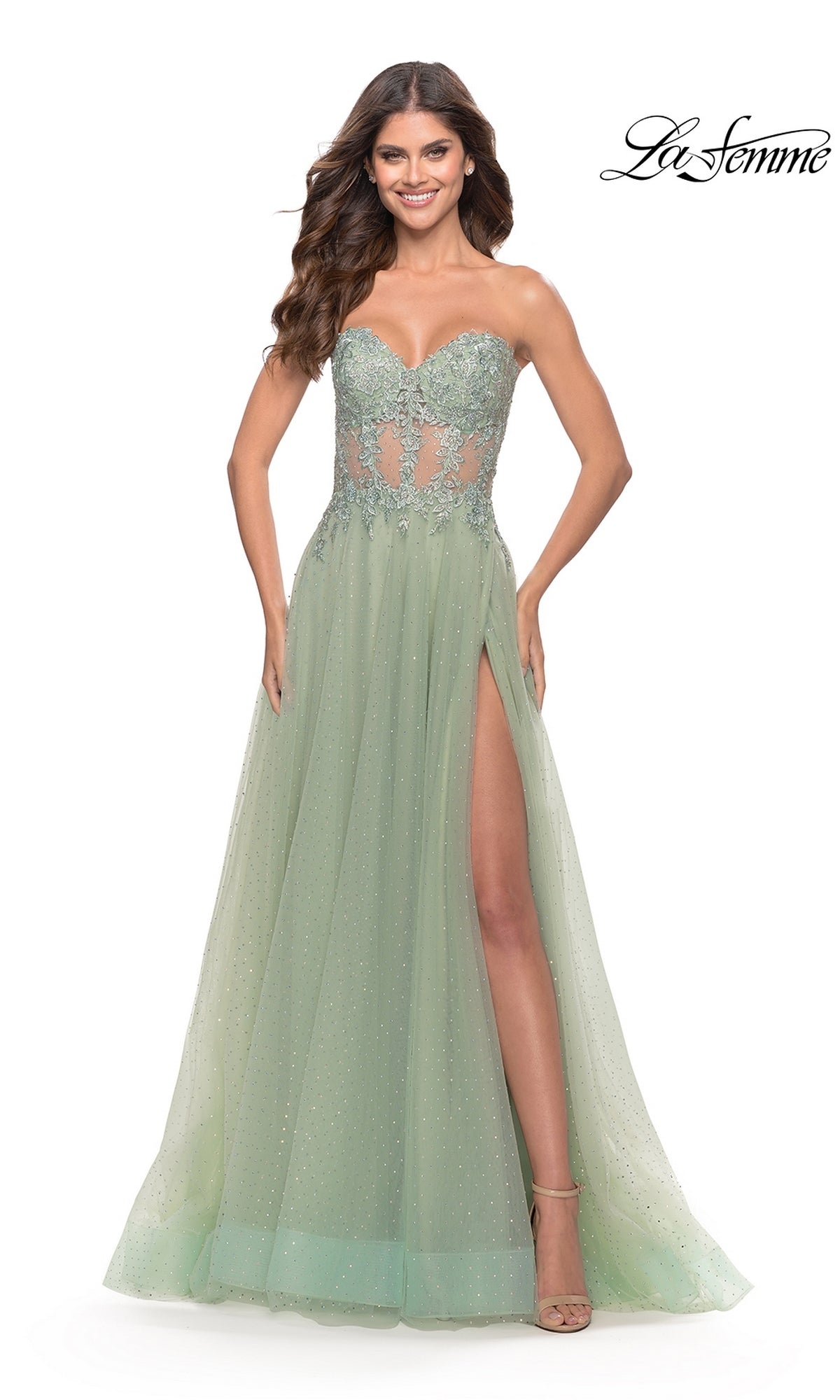 A woman models the La Femme Strapless Sheer-Waist Prom Dress 31367 in light green, featuring a beaded sheer bodice, lace embroidery, an A-line tulle skirt with high slit, against a white background.