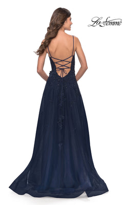 A woman stands facing away from the camera in the La Femme Lace-Bodice Long A-Line Prom Dress 31381, featuring a navy blue embroidered lace bodice with beaded details and a lace-up open back.