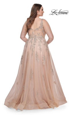 A woman wears the La Femme Long Prom Dress 31383, a sleeveless, floor-length blush pink lace gown with floral embroidery and a sheer back, standing against a white background.