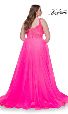 A woman with long brown hair wears the La Femme Long Prom Dress 31394, a sleeveless bright pink gown with an embroidered lace bodice and tulle skirt, shown from the back against a white background.