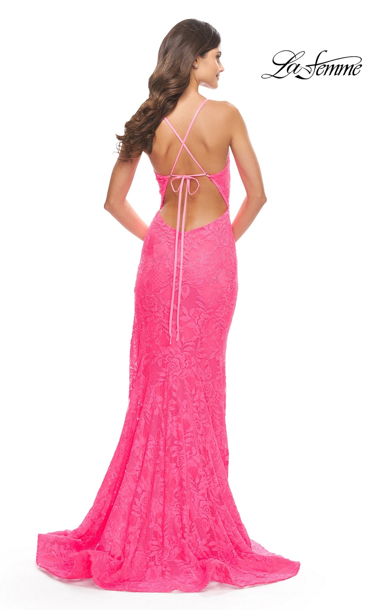 A woman is shown from behind in the Long Lace Mermaid Prom Dress: La Femme 31404, featuring bright pink lace, an open back with crisscross straps, and a floor-length mermaid silhouette. The 