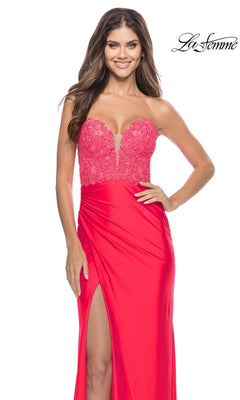 A woman wears the Long Prom Dress: La Femme 31411, a floor-length red gown featuring a lace corset bodice, strapless neckline, and high leg slit.