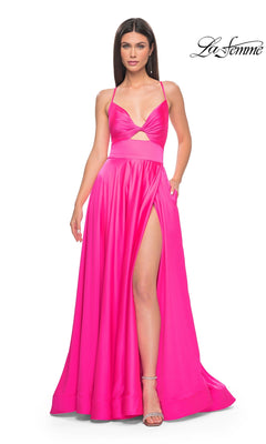 A woman models the La Femme Twist-Front Long A-Line Prom Dress 31412 in bright pink with a high slit and cutout detail, standing against a white background. The La Femme logo appears in the top right corner.