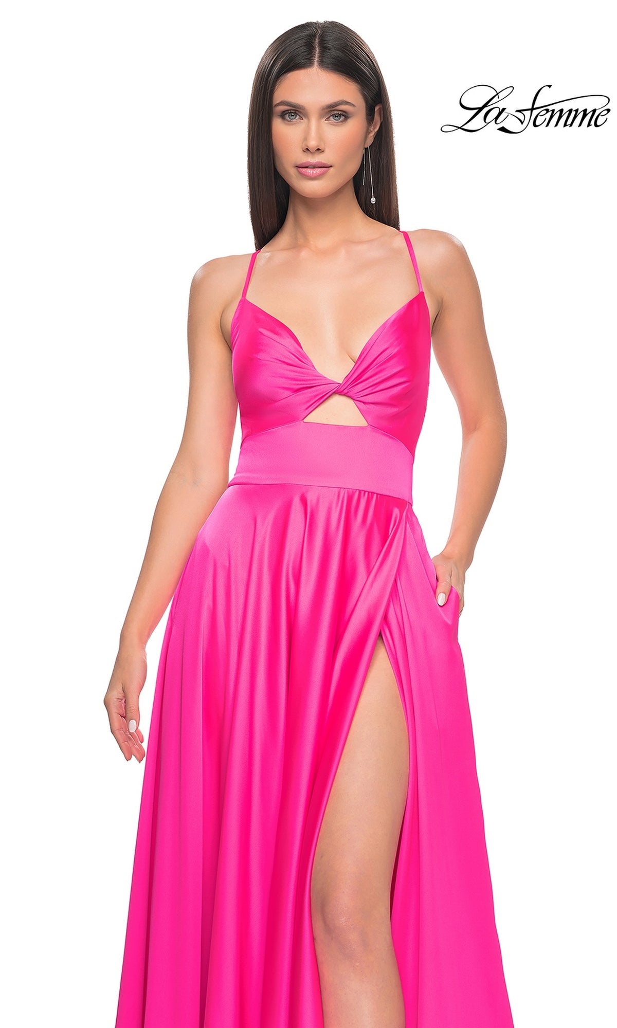 A woman models the La Femme Twist-Front Long A-Line Prom Dress 31412 in bright pink, featuring an open back, front cutout, and high slit, against a white background with the 