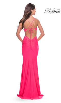 Woman wearing the La Femme 31428 Cut-Out Long Neon Pink Prom Dress, a floor-length backless gown with crisscross straps and ruched details, standing with her back to the camera.