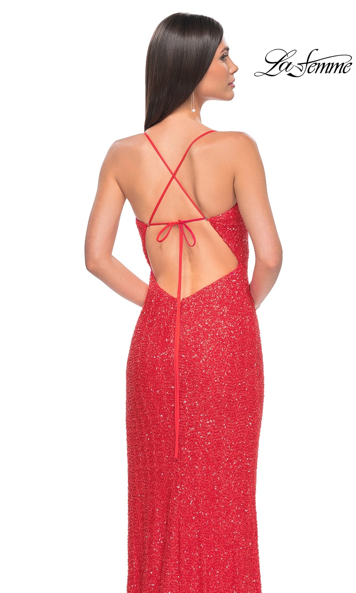 A woman in the La Femme Hot Coral Long Beaded Prom Dress 31432 with crisscrossed straps and a sparkly, backless design faces away from the camera. 