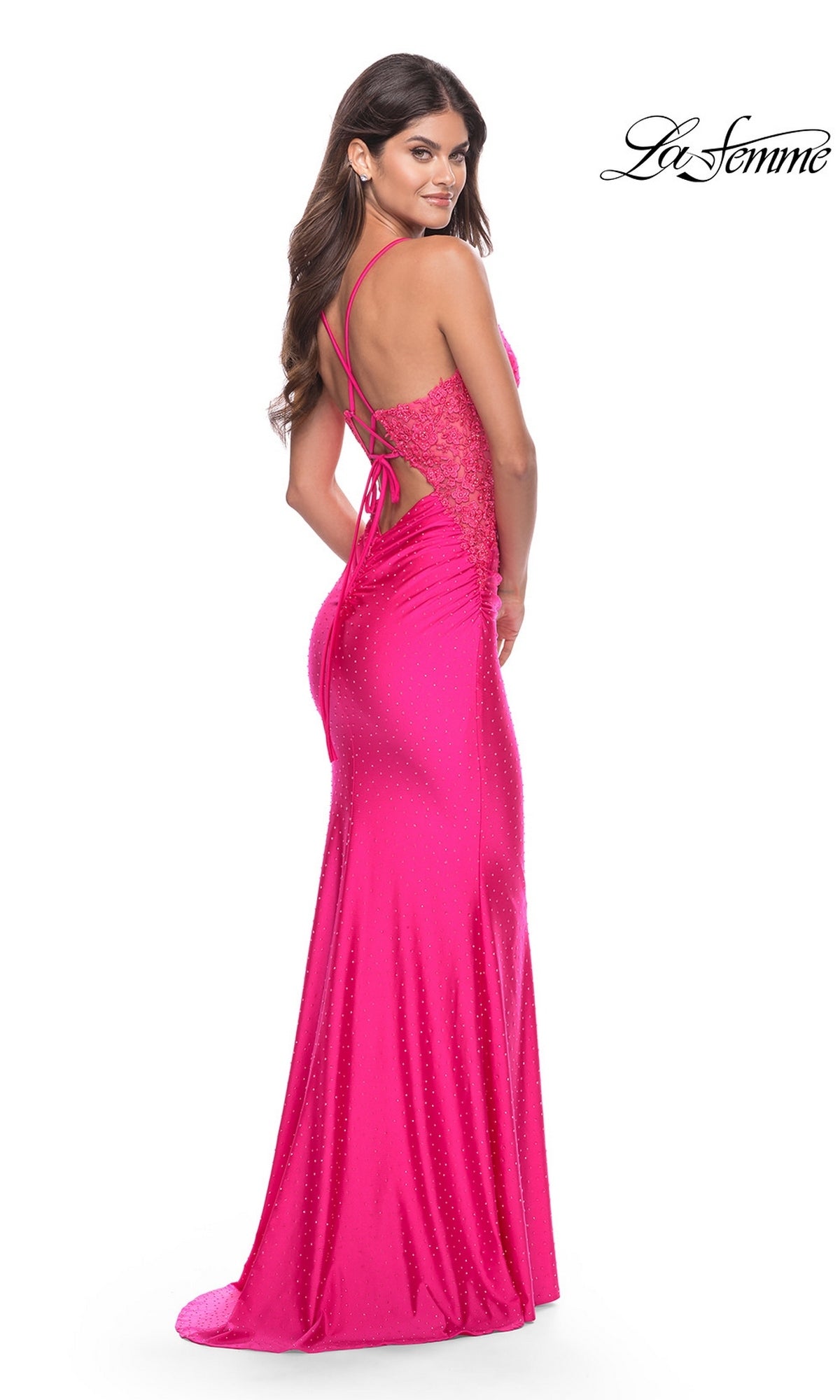 A model wears a hot pink, floor-length ruched Long Prom Dress: La Femme 31436 with a lace bodice, spaghetti straps, and a lace-up back.