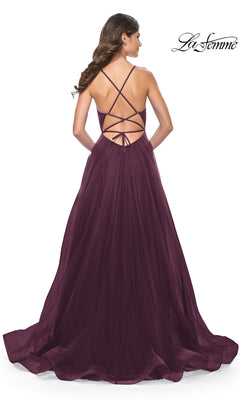A woman faces away in the La Femme Sheer-Waist Long Prom Ball Gown 31457, featuring a floor-length deep purple a-line silhouette with crisscross straps, open back, and an elegant flowing sheer skirt.
