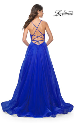 A woman faces away in a bright blue La Femme Sheer-Waist Long Prom Ball Gown 31457, featuring an a-line silhouette, strappy open back, and flowing tulle floor-length skirt.