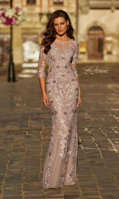 A woman wearing the La Femme 31464 long formal dress in mauve with three-quarter sleeves and light-colored floral lace embroidery stands on a cobblestone street.