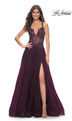 A woman smiles in the La Femme Beaded-Bodice Long A-Line Prom Gown 31471, featuring a deep burgundy hue, lace bodice, plunging neckline, and high slit.