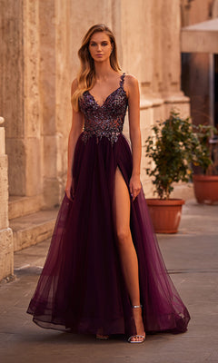 A woman wears the La Femme Beaded-Bodice Long A-Line Prom Gown 31471, featuring a sleeveless deep purple v-neck, beaded bodice, and high slit, as she stands on a stone pathway near potted plants and a building.