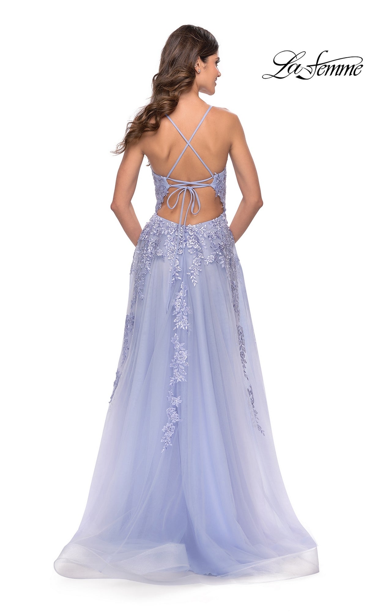 A woman in the La Femme Strappy-Back Long A-Line Prom Dress 31503, featuring light purple floral lace and a crisscross strappy-back, stands facing away.