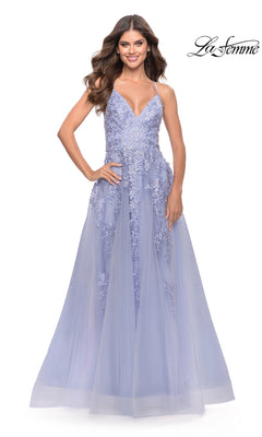 A woman stands smiling against a white background with the "La Femme" logo, wearing the La Femme Strappy-Back Long A-Line Prom Dress 31503, featuring thin straps, floral lace details, and lavender embellished fabric.