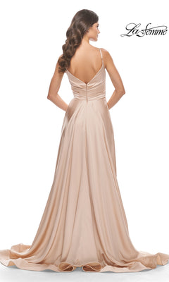 A woman is shown from the back wearing the La Femme V-Neck Long A-Line Prom Dress 31505 in light beige satin, featuring thin straps, a V-shaped back, and a flowing train.