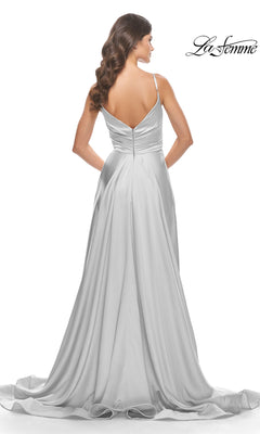 A woman wears the La Femme V-Neck Long A-Line Prom Dress 31505, a floor-length silver satin gown with thin straps, V-shaped back, and flowing train, standing against a white background.