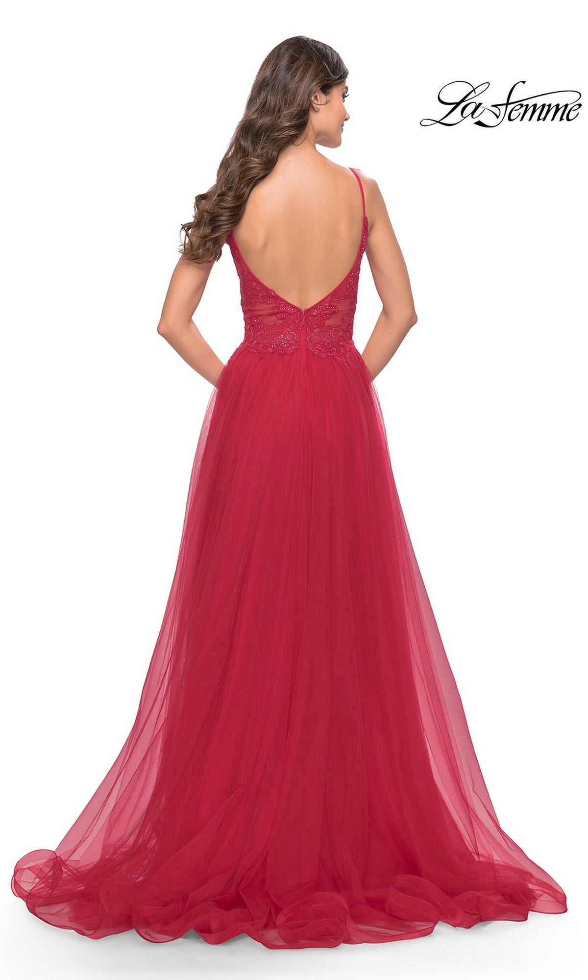 A woman with long wavy brown hair is seen from behind in the Lace-Bodice Long Tulle Prom Dress: La Femme 31507—a floor-length, sleeveless red A-line tulle gown with a low back. The La Femme logo appears in the top right corner.