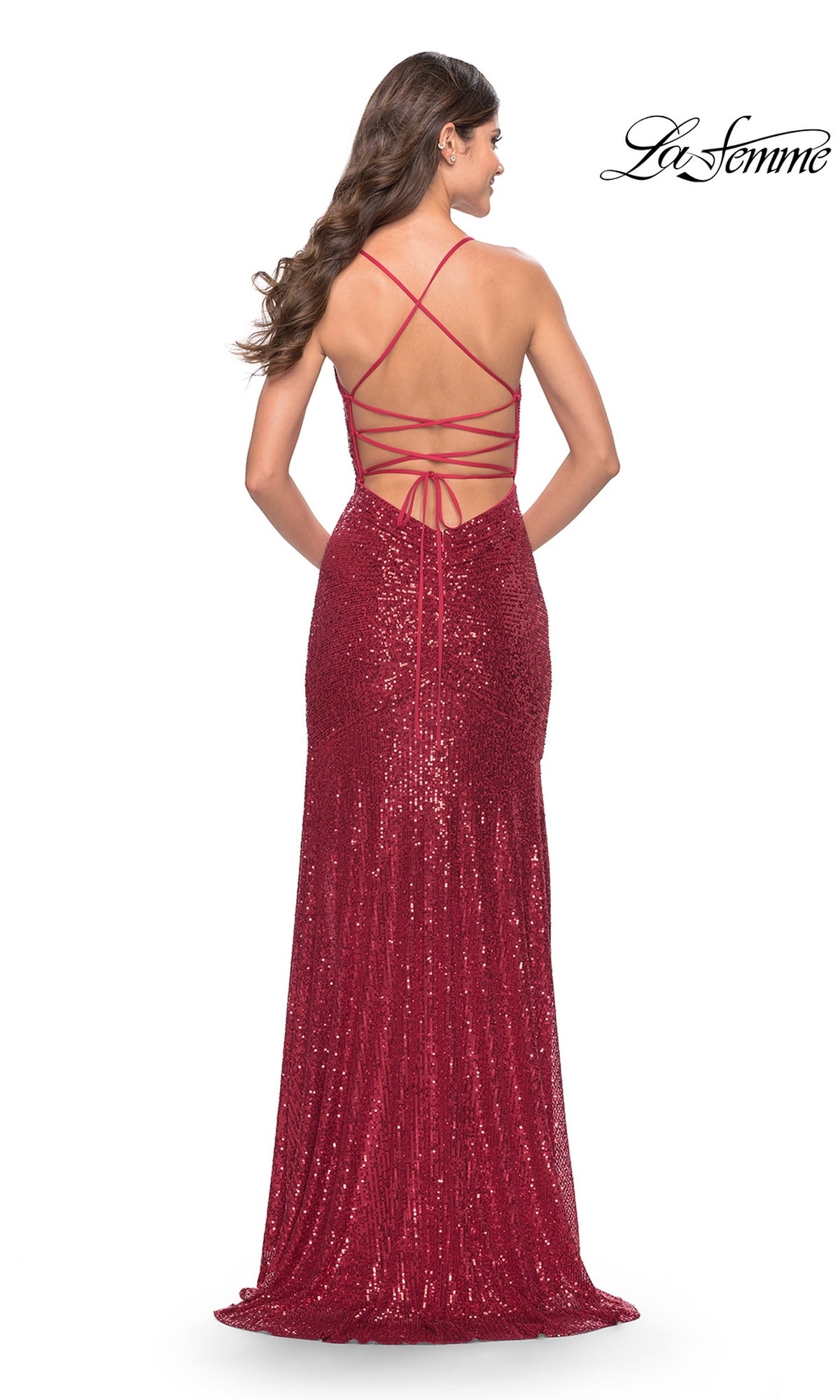 A woman faces away from the camera in the Strappy Long Sequin Prom Dress: La Femme 31508, a floor-length red gown with open back and lace-up detail. The La Femme logo is displayed in the top right corner.