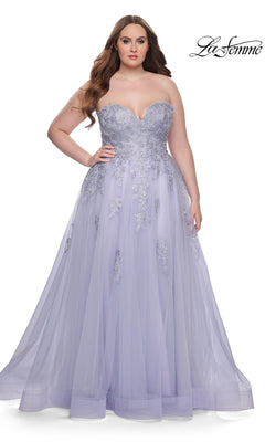 A woman models the La Femme Long Prom Dress 31570, a lavender plus-size strapless gown with silver floral embellishments and a corset-style bodice, standing against a white background.