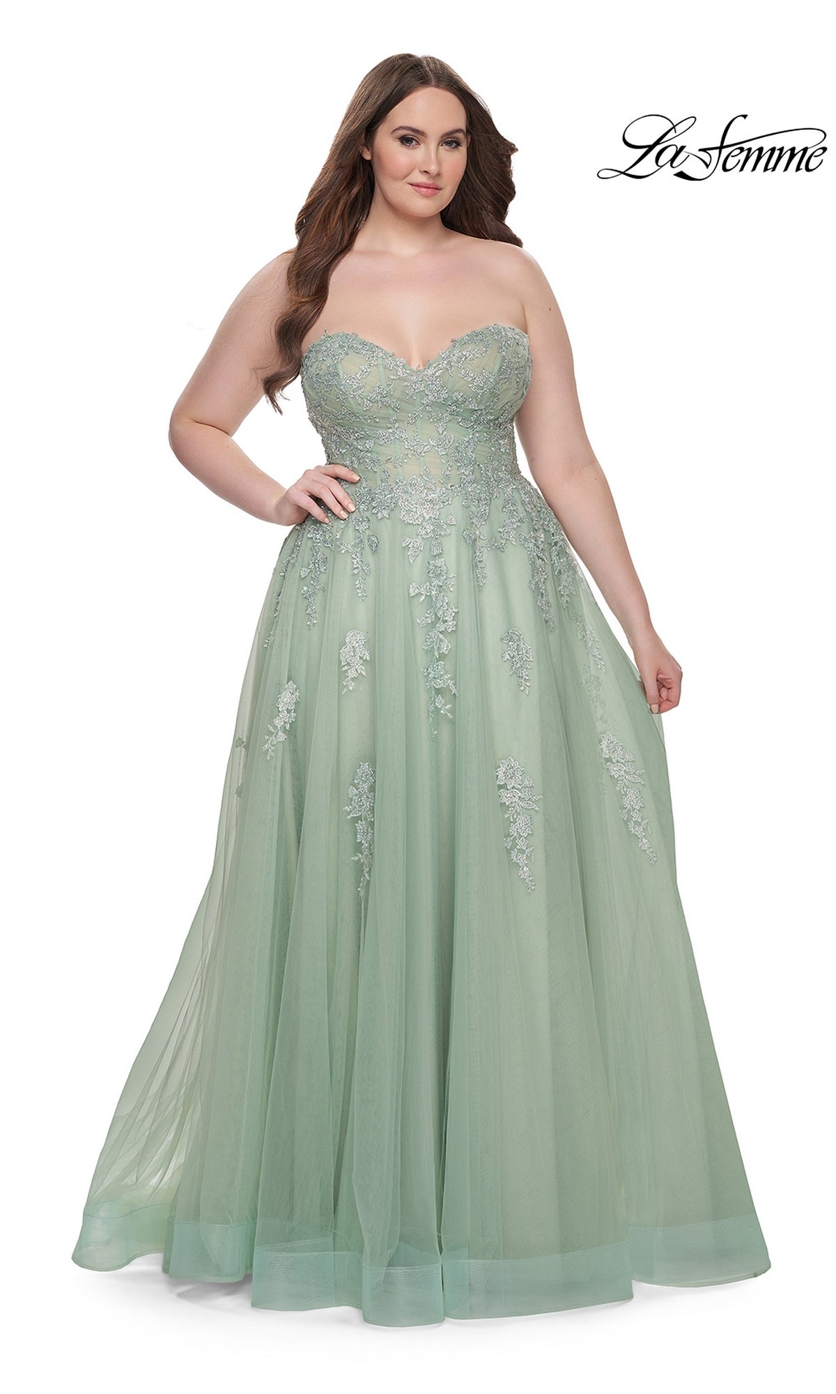 A woman poses against a white backdrop wearing the La Femme Long Prom Dress 31570, a strapless pastel green floor-length gown with a corset-style bodice and floral embroidered lace on the tulle skirt.