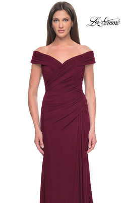 Against a plain white background, a woman wears the La Femme Off-the-Shoulder Long Prom Dress 31677 in burgundy with ruched detailing. The "La Femme" logo appears in the top right, highlighting this elegant evening gown.