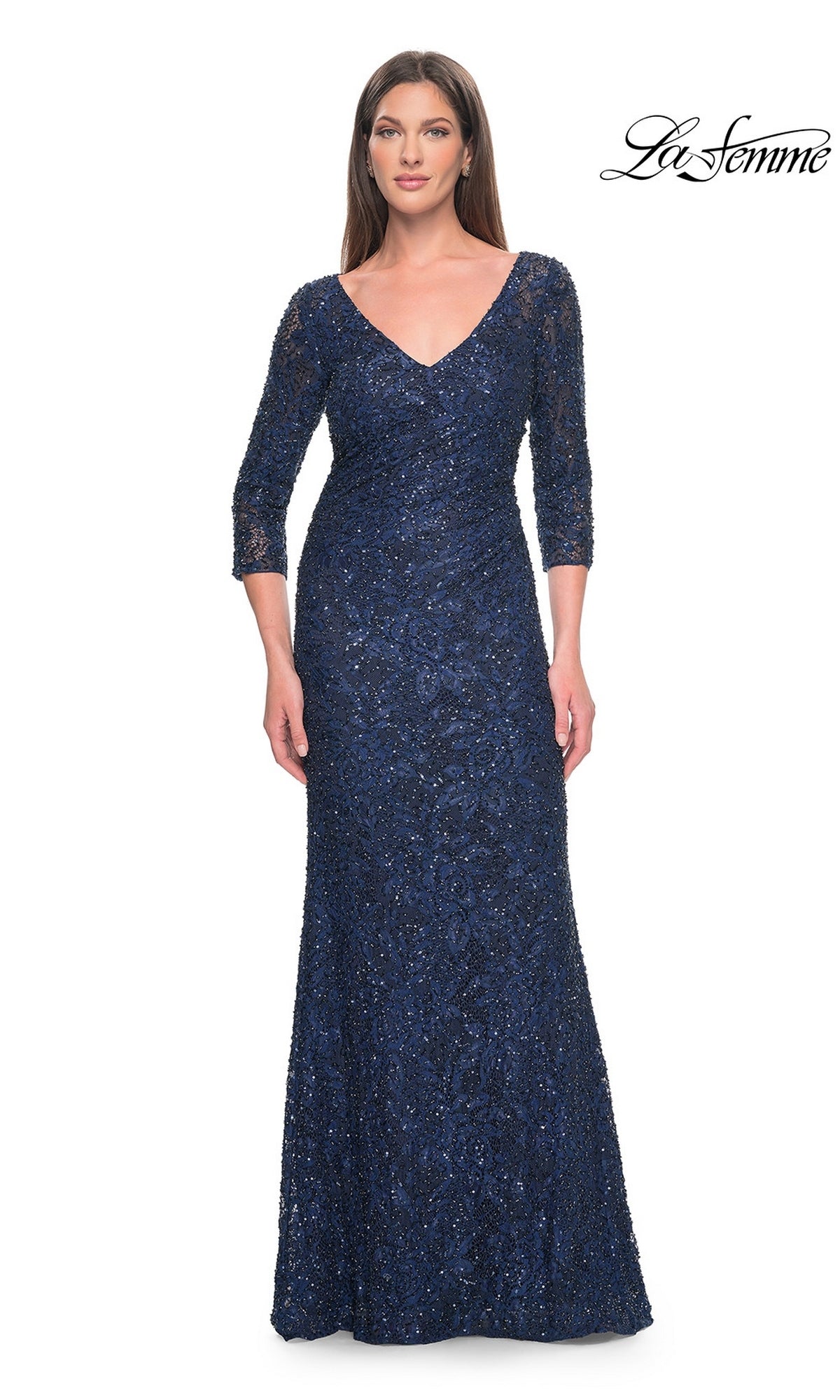 A woman wears the Long Formal Dress: La Femme 31721, a floor-length, navy blue V-neck dress featuring three-quarter sleeves and a sequined lace overlay.