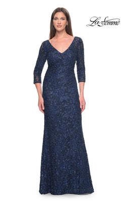 A woman wears the Long Formal Dress: La Femme 31721, a floor-length, navy blue V-neck dress featuring three-quarter sleeves and a sequined lace overlay.