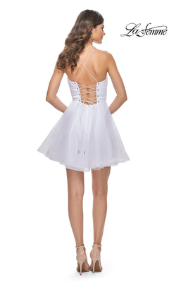 A woman stands facing away, wearing the A-Line Short Corset Homecoming Dress 31763 featuring a lace-up back and spaghetti straps, styled with nude heels.