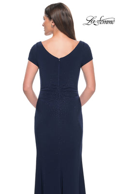 Back view of a woman wearing a dark blue, short-sleeved rhinestone La Femme 31773 formal dress with a v-neck and scattered bead embellishments.