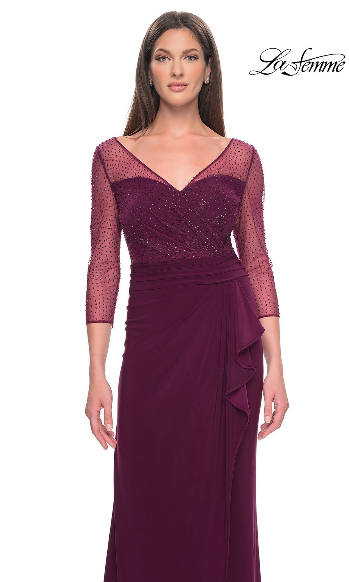 A woman wears a Long Formal Dress: La Femme 31777 in deep purple, featuring a sheer, beaded bodice and a floor-length draped skirt with a side ruffle.