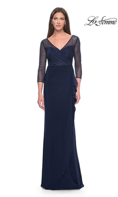 The La Femme 31777 is a navy blue long jersey formal dress featuring a V-neck bodice, three-quarter length sleeves, a sheer beaded overlay, and a draped skirt with a side ruffle.