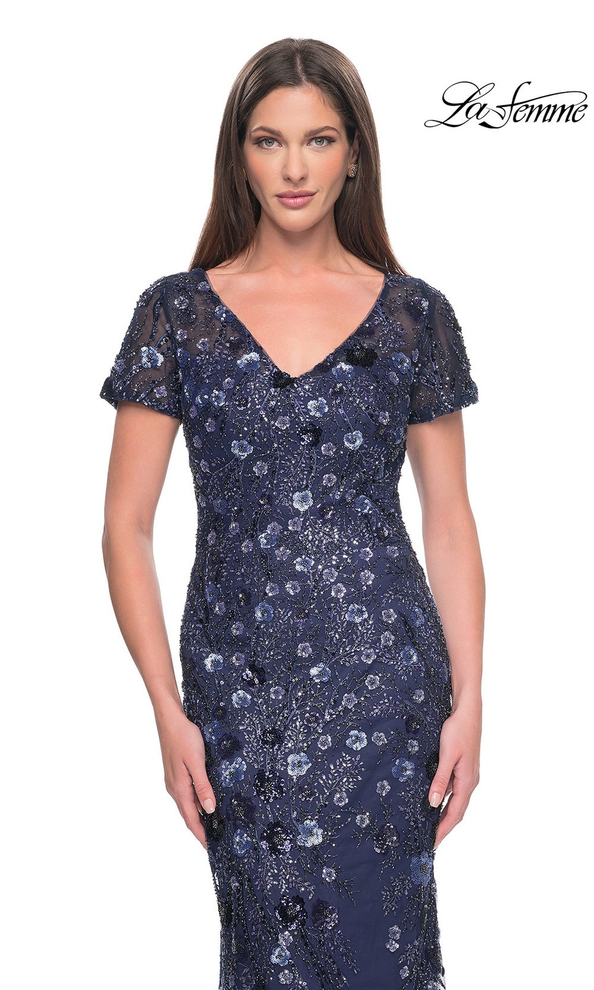 A woman wears a La Femme 31779 long formal dress, a navy blue, V-neck, short-sleeved gown featuring intricate sequin floral beadwork throughout.